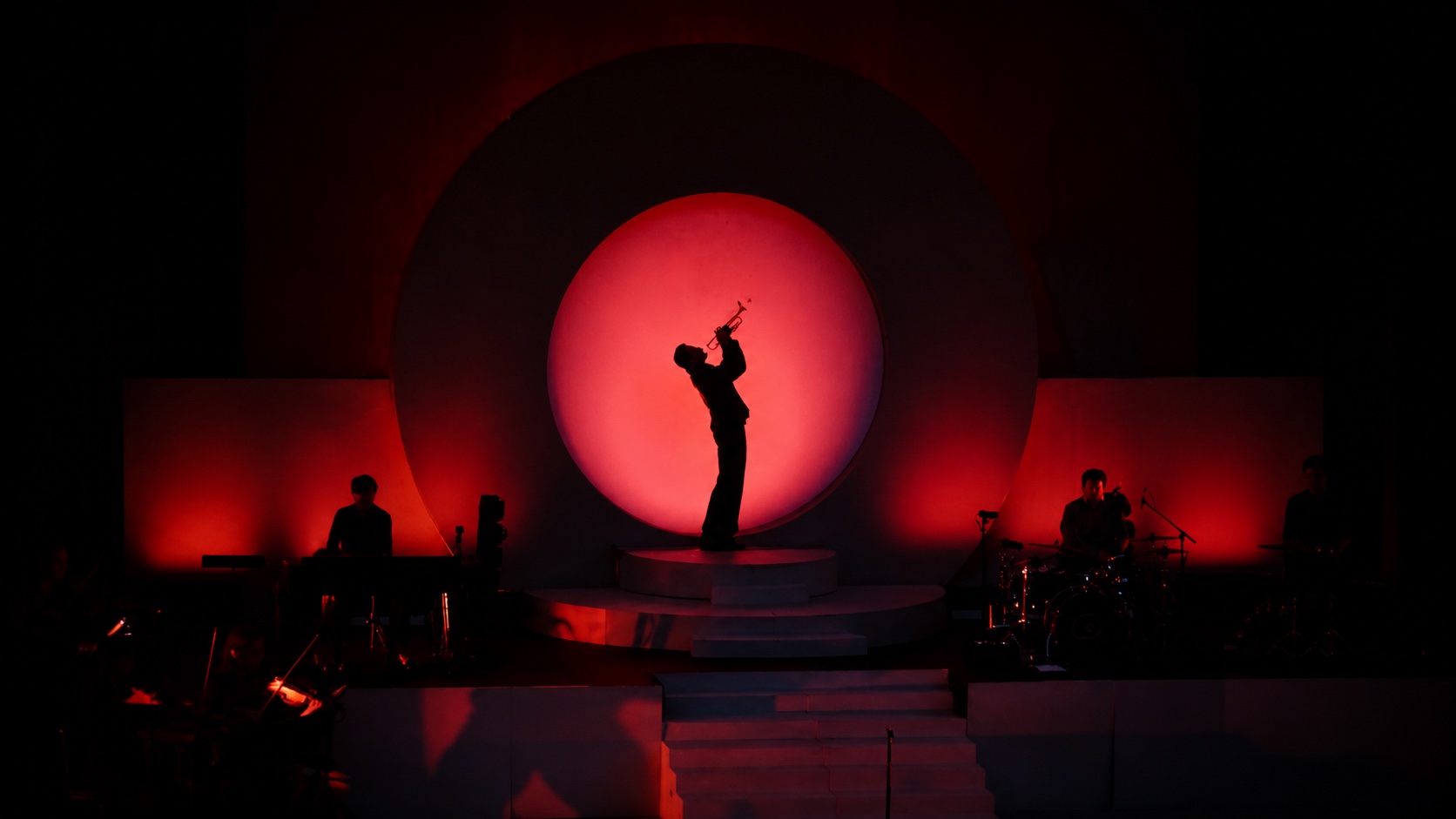 Trompetista iluminado en un escenario rojo